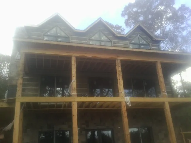 Dormers and porch framing on a large log home under construction — Roof Coating work by our crew in Melvin