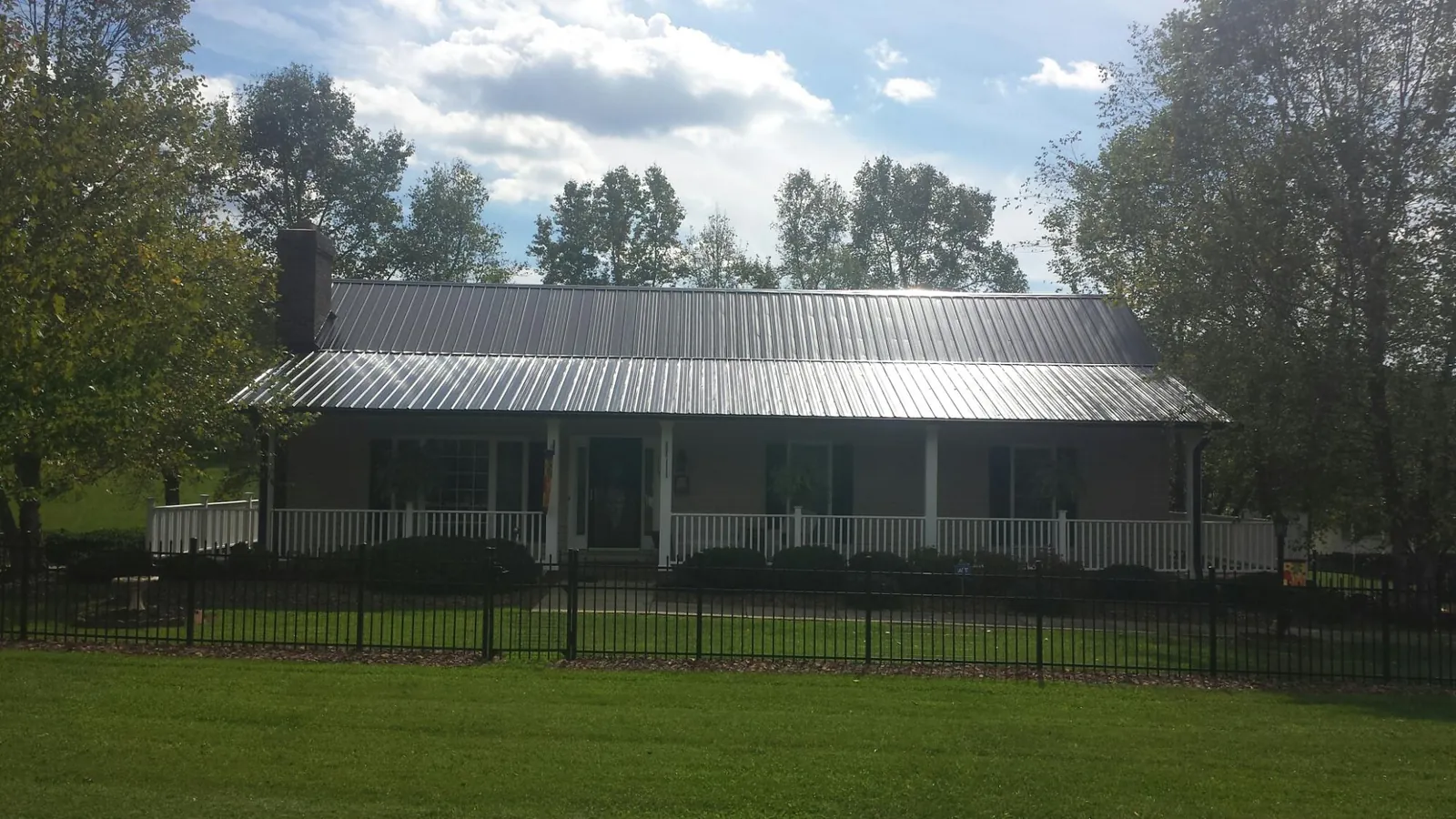 Gray metal roof on a brick ranch with a full width front porch — Gutter Guard Installation work by our crew in Melvin