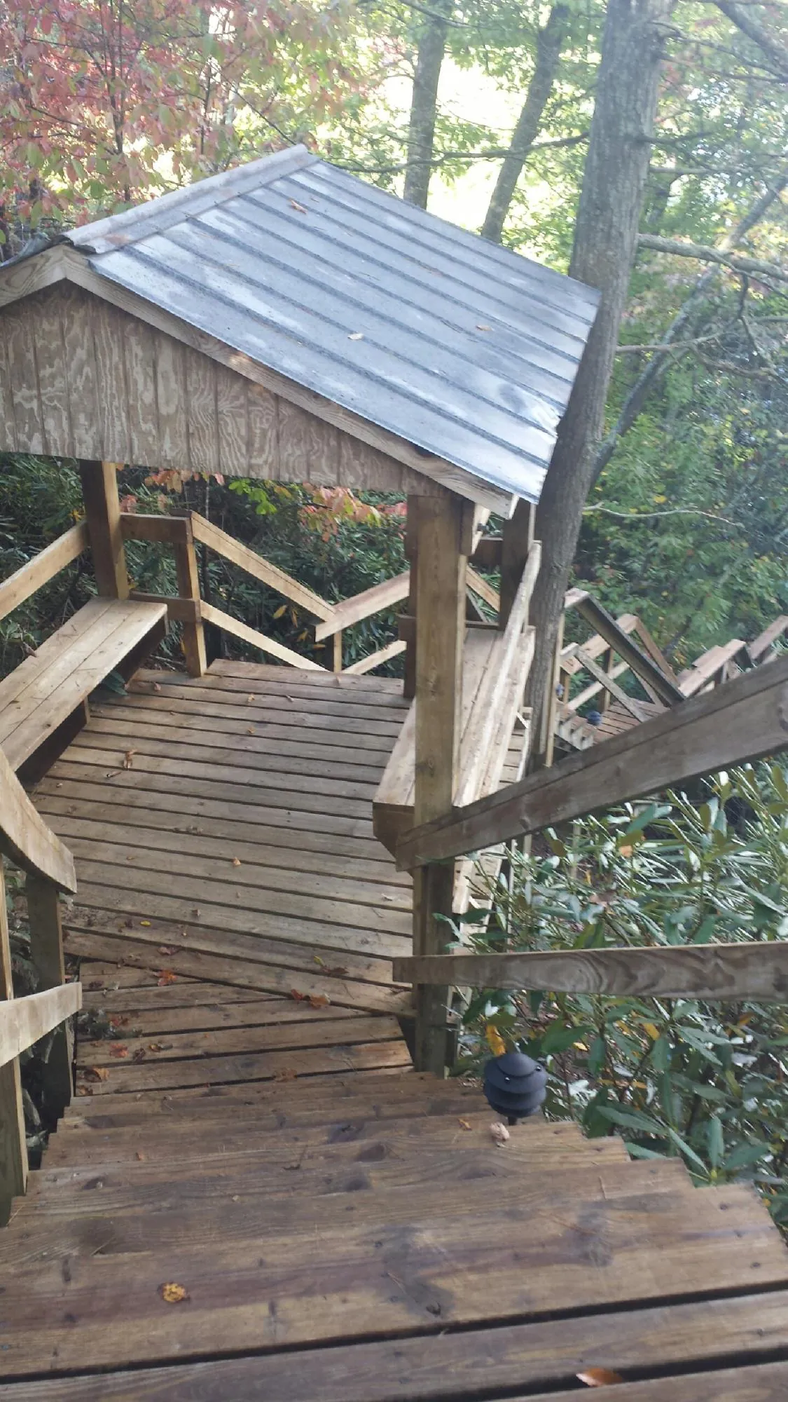 Metal roofed shelter over wooden steps on a wooded walkway — Skylight Repair & Installation work by our crew in Melvin