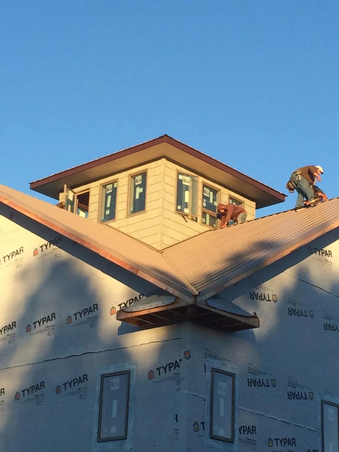 Roofers working around a rooftop cupola on a new metal roof at sunset — Roof Waterproofing in Melvin by Roofing Brothers
